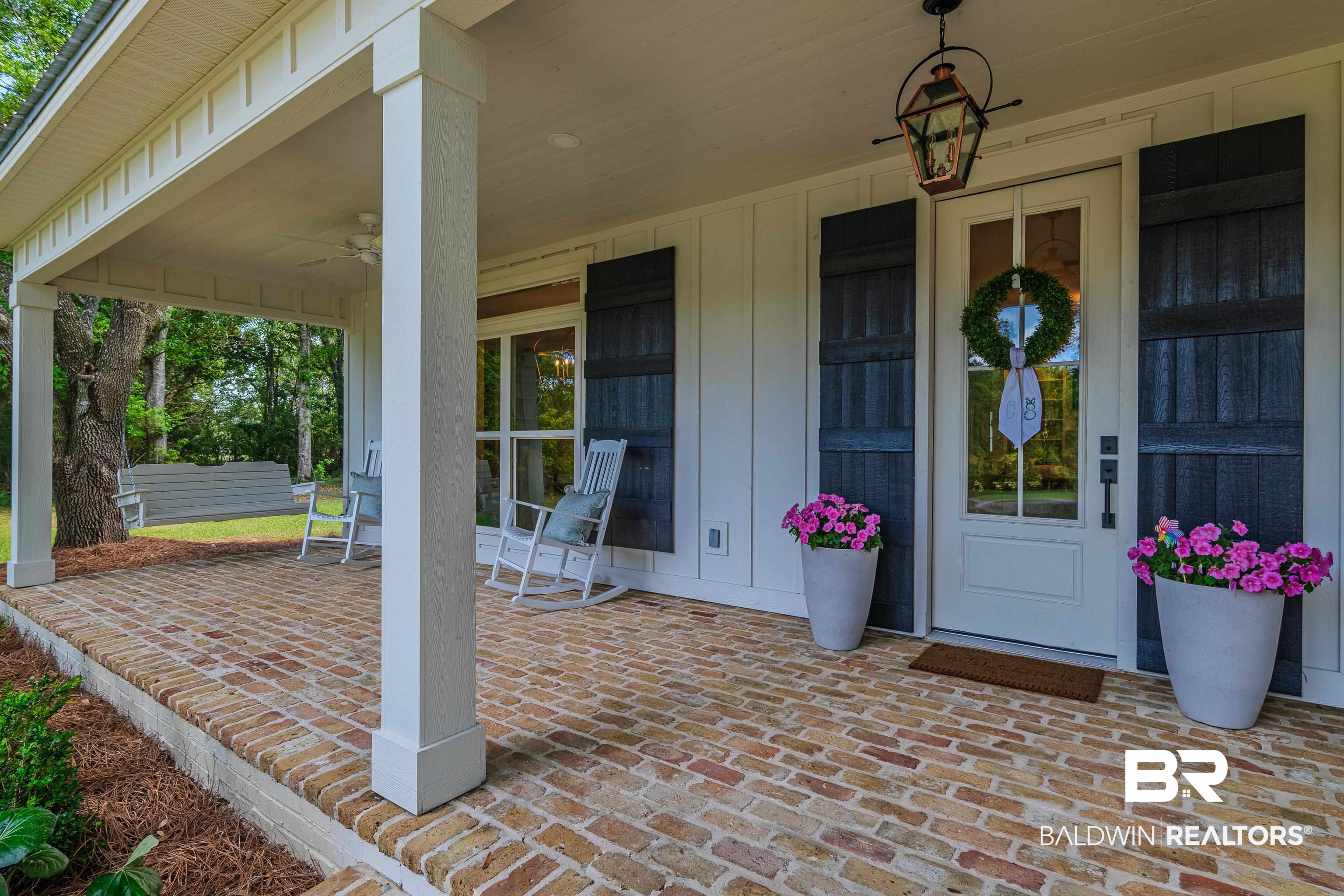 19121 Boothe Road Fairhope, AL 36532 - Photo 4 of 41 Property entrance with ceiling fan, covered porch, and board and batten siding
