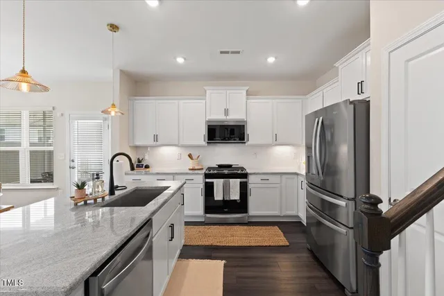a kitchen with stainless steel appliances granite countertop a refrigerator a sink and a stove