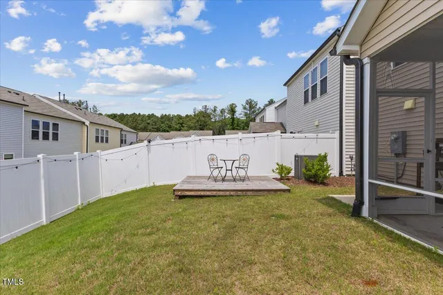 a view of a backyard with wooden fence and a large tree