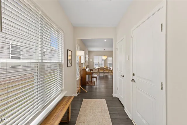 a hallway with a dining table wooden floor and a window
