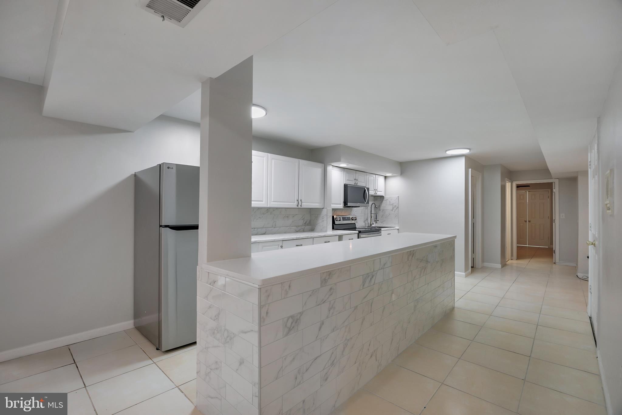 16729 Queen Anne Road Upper Marlboro, MD 20774 - Photo 13 of 29 a large white kitchen with a sink and refrigerator