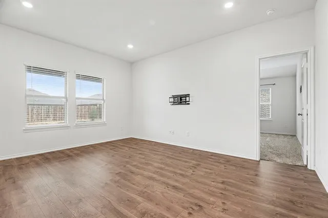 a view of an empty room with wooden floor and a window