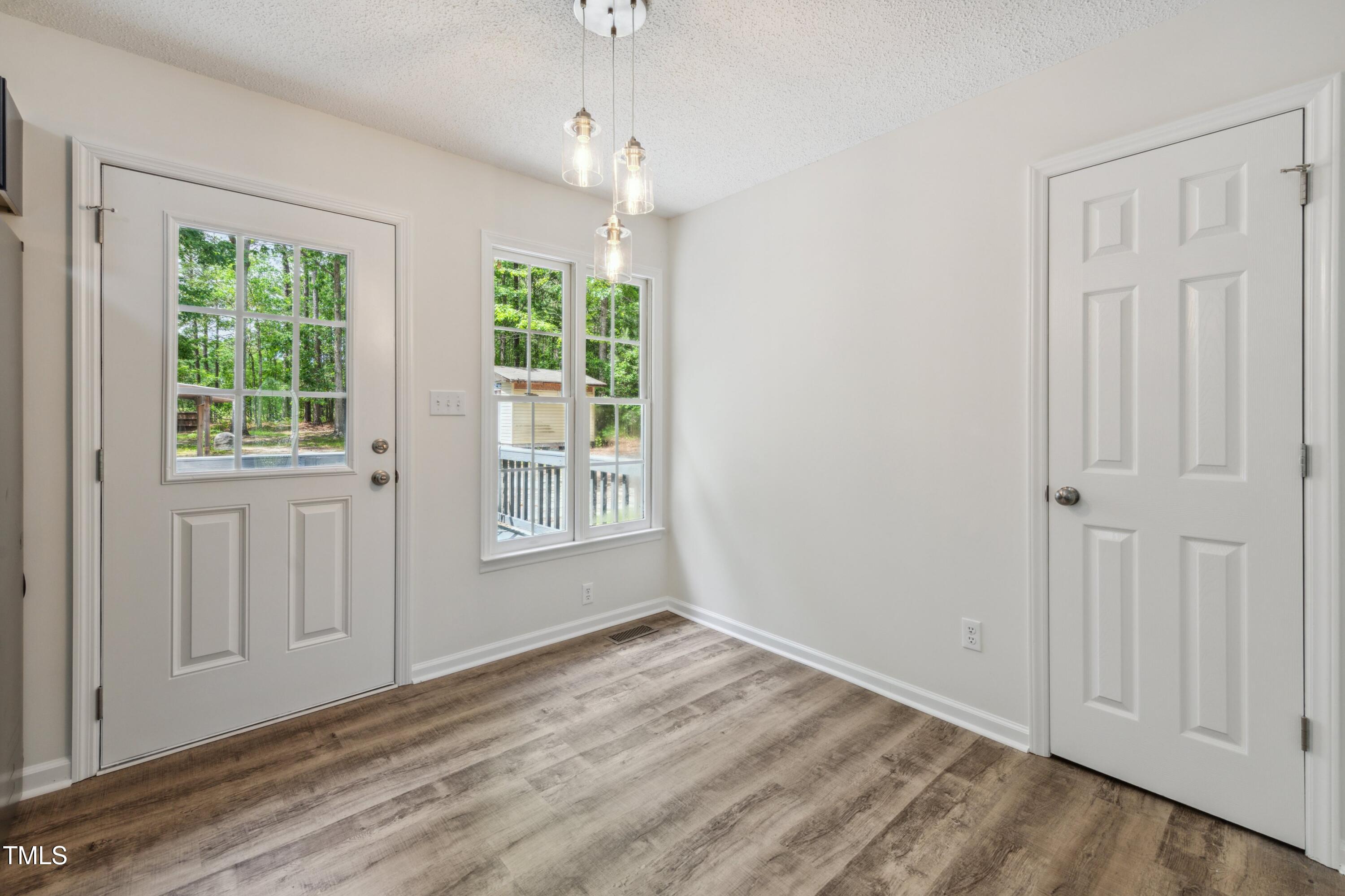 856 Williams-White Road Zebulon, NC 27597 - Photo 9 of 38 an empty room with wooden floor cabinet and windows