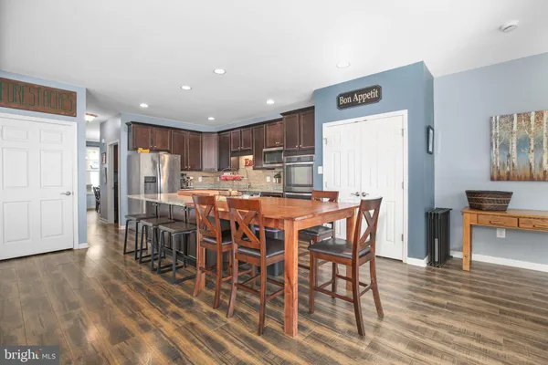 a kitchen with stainless steel appliances kitchen island granite countertop a table chairs sink and cabinets