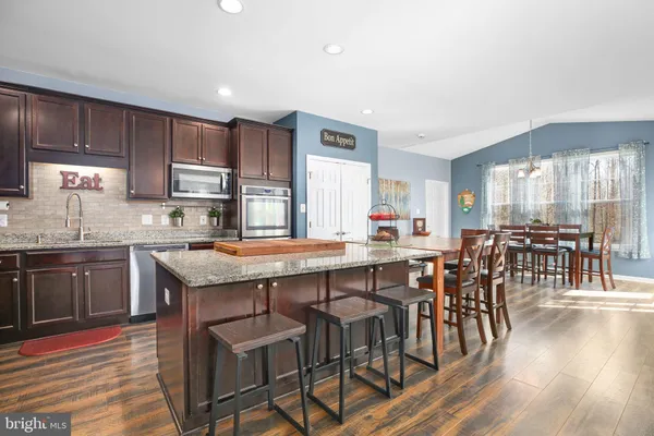 a kitchen with stainless steel appliances granite countertop a refrigerator a sink dishwasher a stove with wooden cabinets