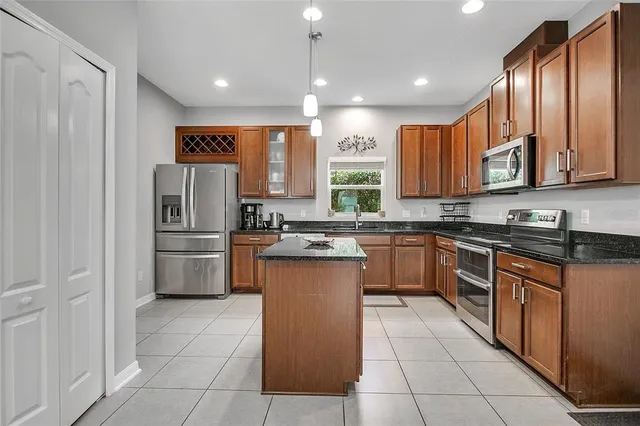a kitchen with stainless steel appliances granite countertop a refrigerator a stove and a sink