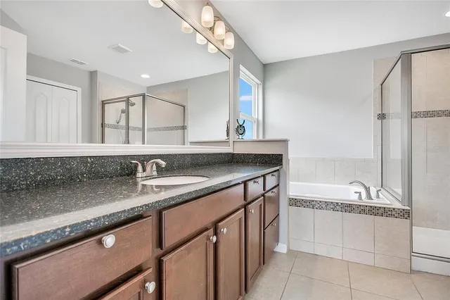 a bathroom with a granite countertop sink a mirror and a bathtub