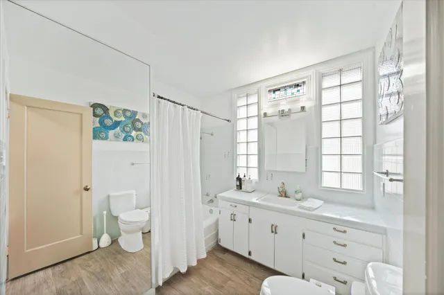 a spacious bathroom with a double vanity sink a toilet and a shower