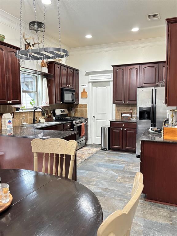 605 Jade Haughton, LA 71037 - Photo 5 of 34 Kitchen featuring dark wood cabinetry, stainless steel appliances, tiled backsplash,and slate looking tile floors