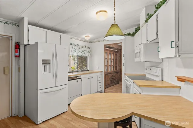 a kitchen with stainless steel appliances granite countertop a refrigerator a sink dishwasher a stove a dining table and chairs with wooden floor