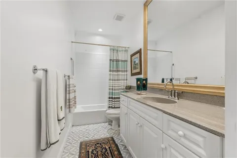 a bathroom with a sink a toilet a mirror and shower