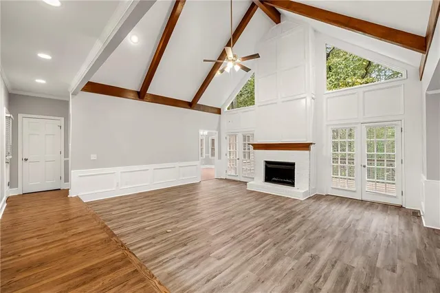a view of an empty room with wooden floor fireplace and a window