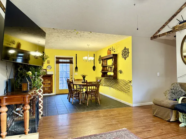 a living room with couches a fireplace and a dining table with wooden floor