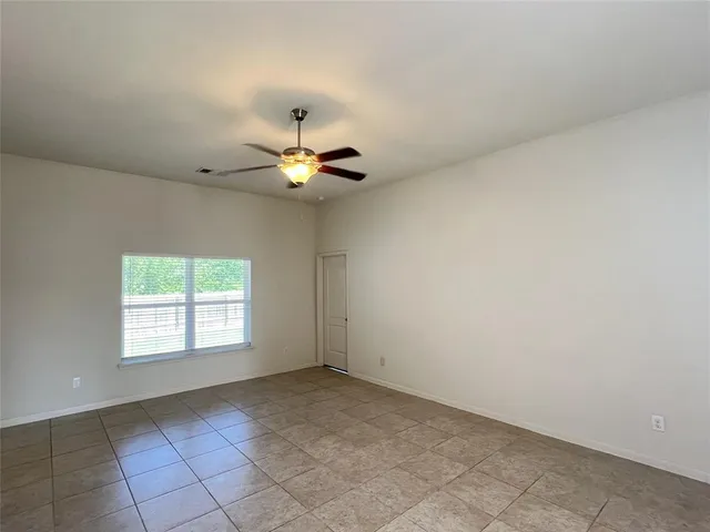 an empty room with windows and chandelier fan