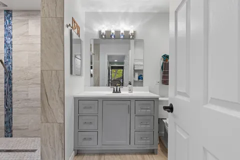 a bathroom with a granite countertop sink a large mirror and a shower