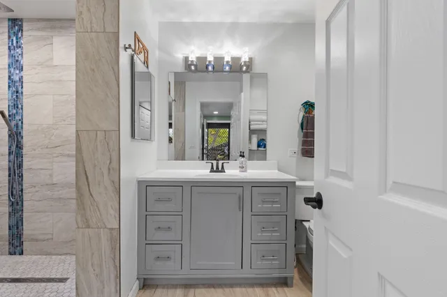a bathroom with a granite countertop sink a large mirror and a shower