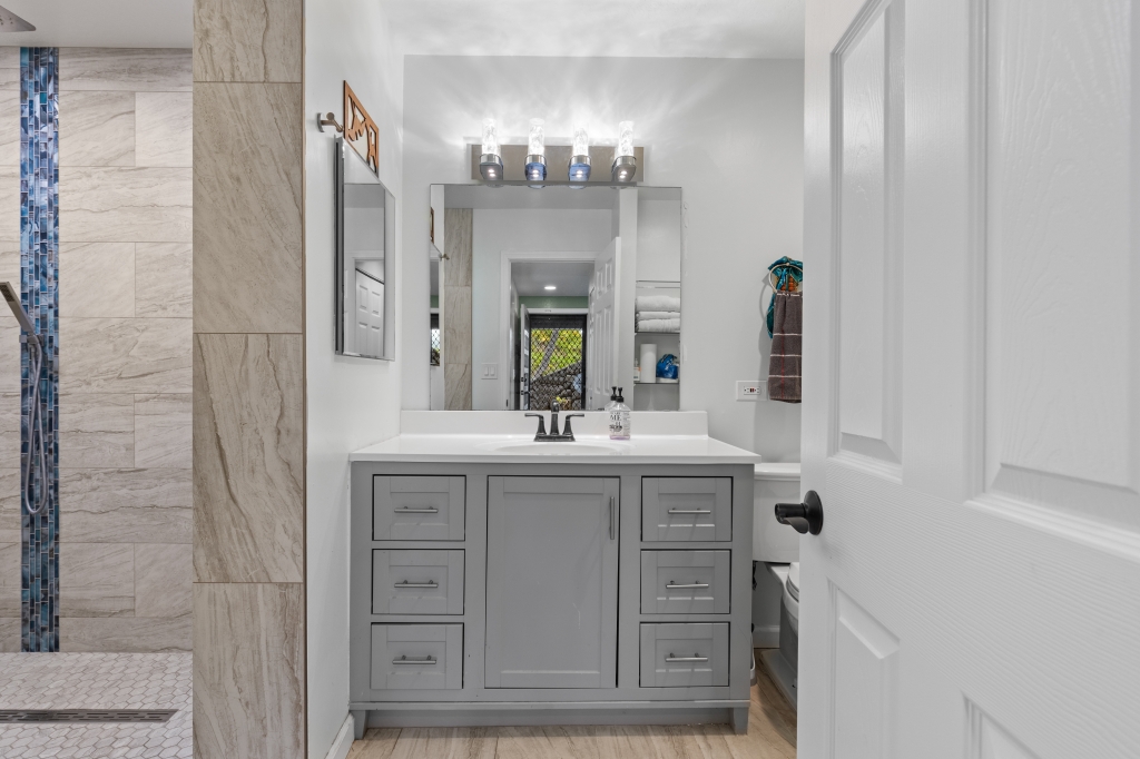 95-789 Ninole Loop Road, Unit 42 Naalehu, HI 96772 - Photo 11 of 30 a bathroom with a granite countertop sink a large mirror and a shower