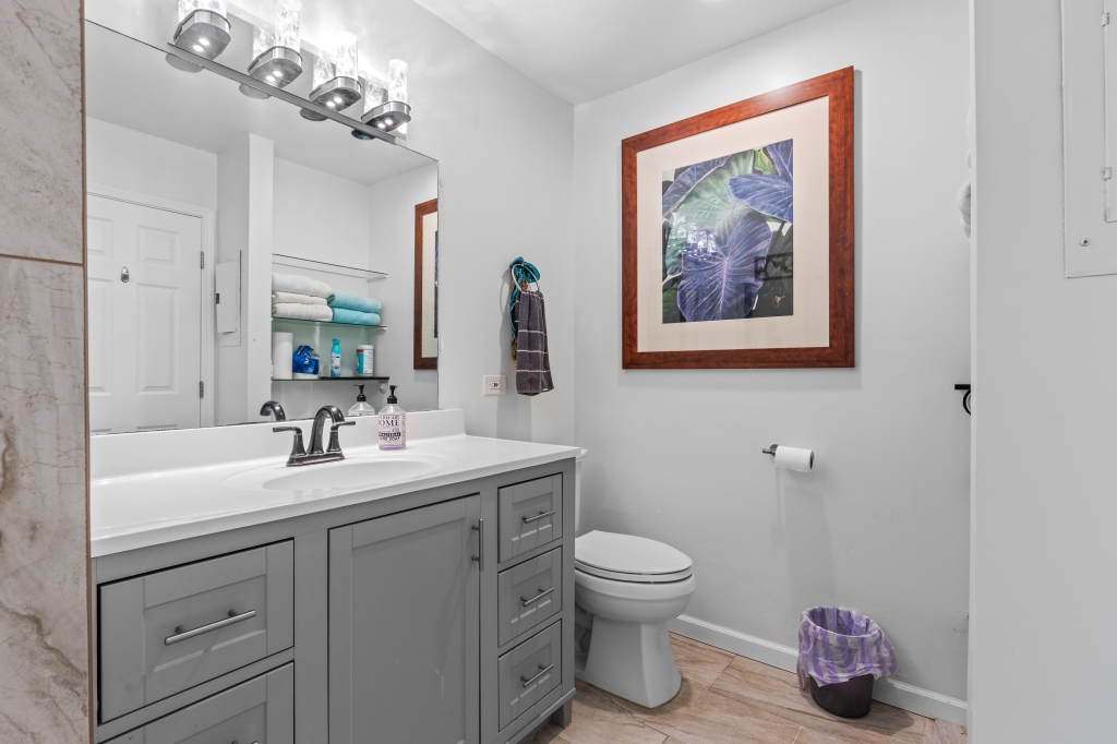 95-789 Ninole Loop Road, Unit 42 Naalehu, HI 96772 - Photo 12 of 30 a bathroom with a toilet sink and mirror