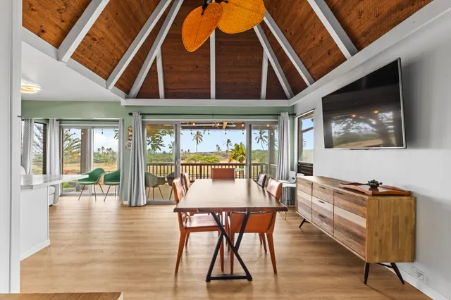 a dining room with wooden floor and large windows