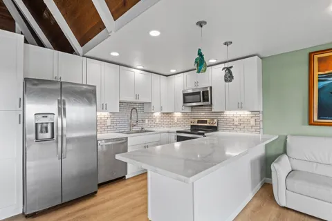 a kitchen with granite countertop a refrigerator a sink dishwasher a oven with a dining table and chairs