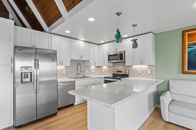 a kitchen with granite countertop a refrigerator a sink dishwasher a oven with a dining table and chairs