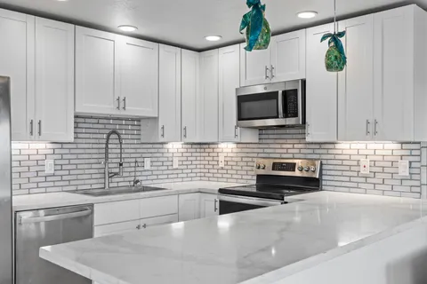 a kitchen with granite countertop a sink a stove and cabinets