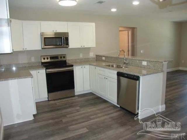a kitchen with stainless steel appliances granite countertop a stove top oven a sink and a microwave