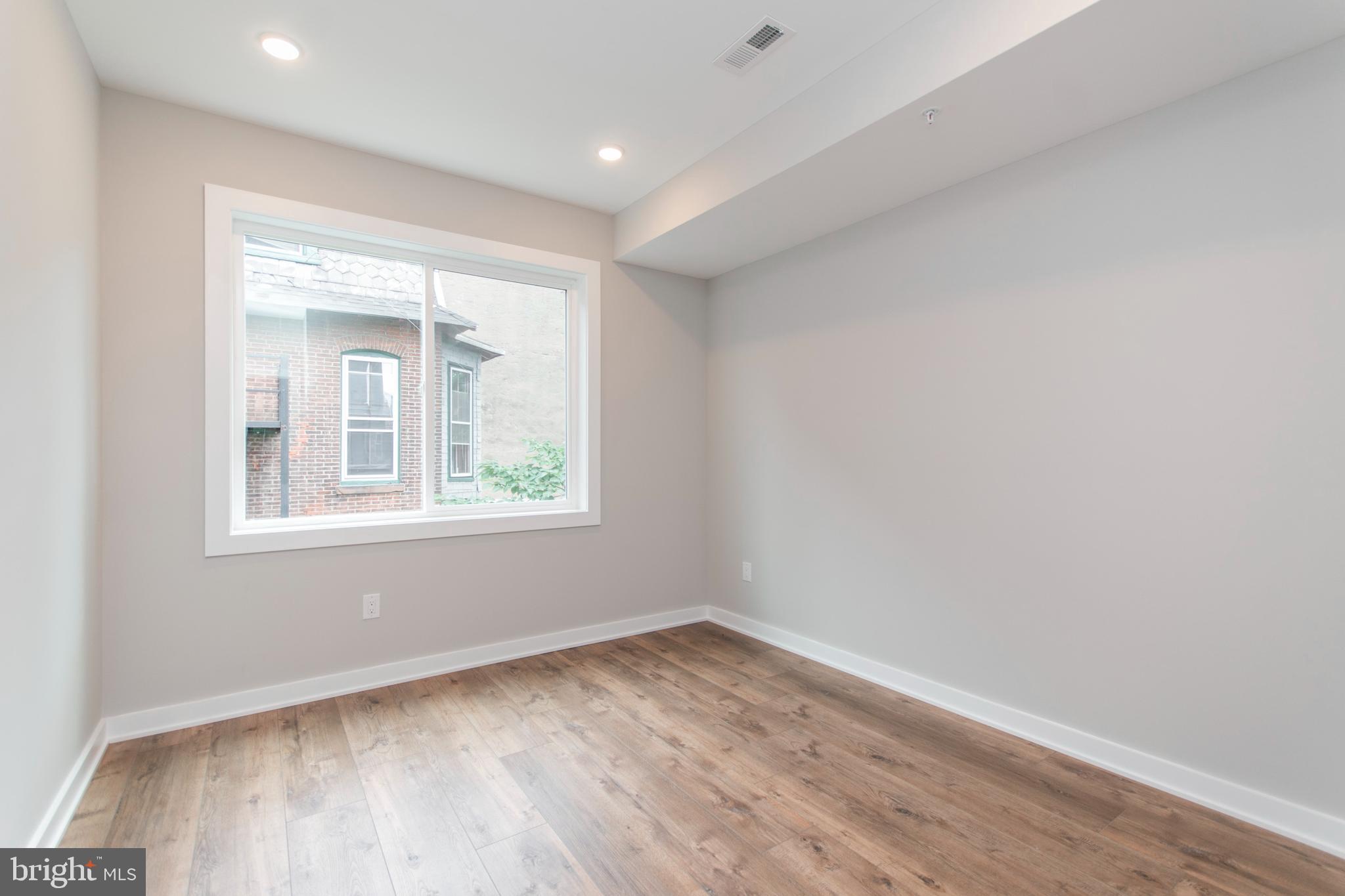 437 North 35th Street, Unit C Philadelphia, PA 19104 - Photo 4 of 9 an empty room with wooden floor and a window