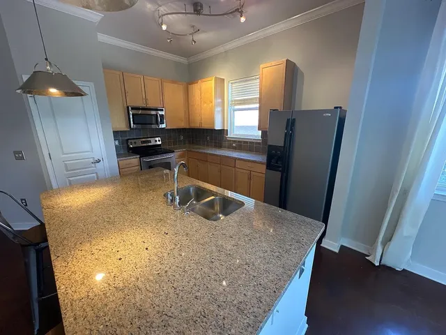 a kitchen with stainless steel appliances granite countertop a refrigerator a stove a sink a counter space and wooden floor