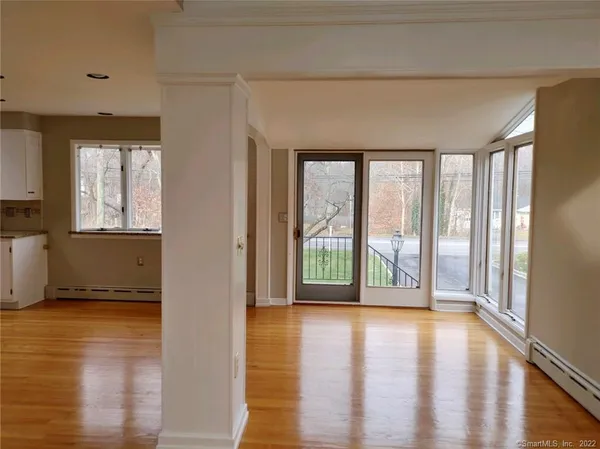 a view of an empty room with wooden floor and a window