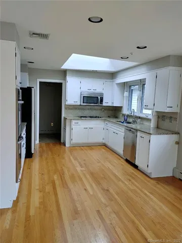 a large kitchen with stainless steel appliances granite countertop a stove a sink dishwasher and a refrigerator