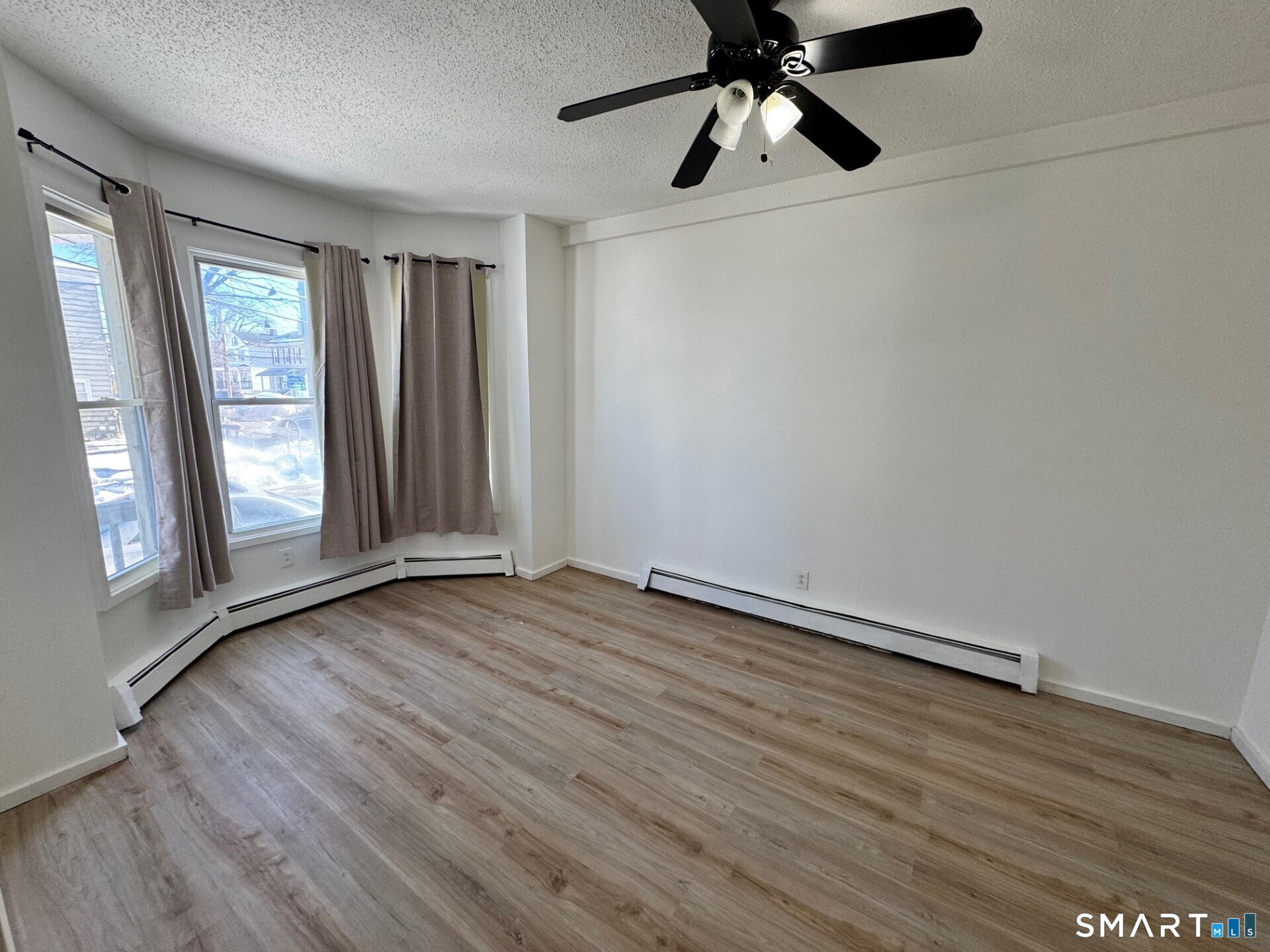 an empty room with wooden floor fan and windows