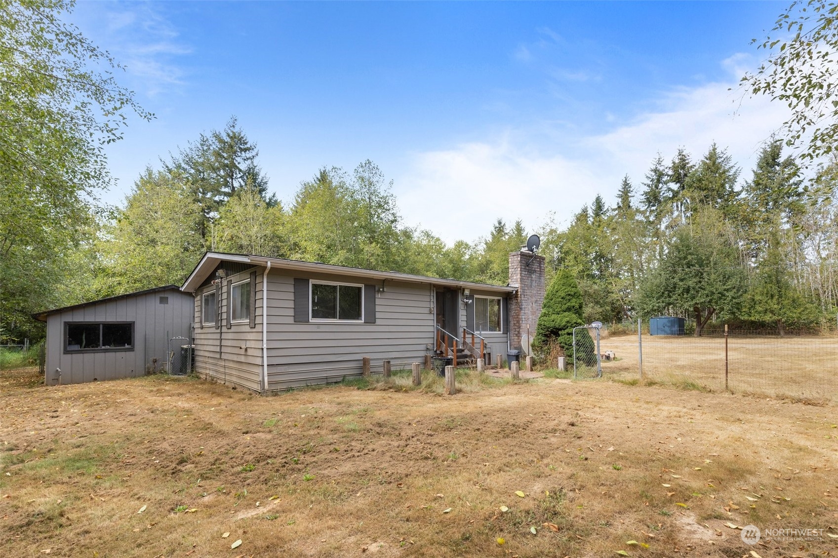 1001 Logan Hill Road Chehalis, WA 98532 - Photo 20 of 23 a backyard of a house with wooden fence and large trees