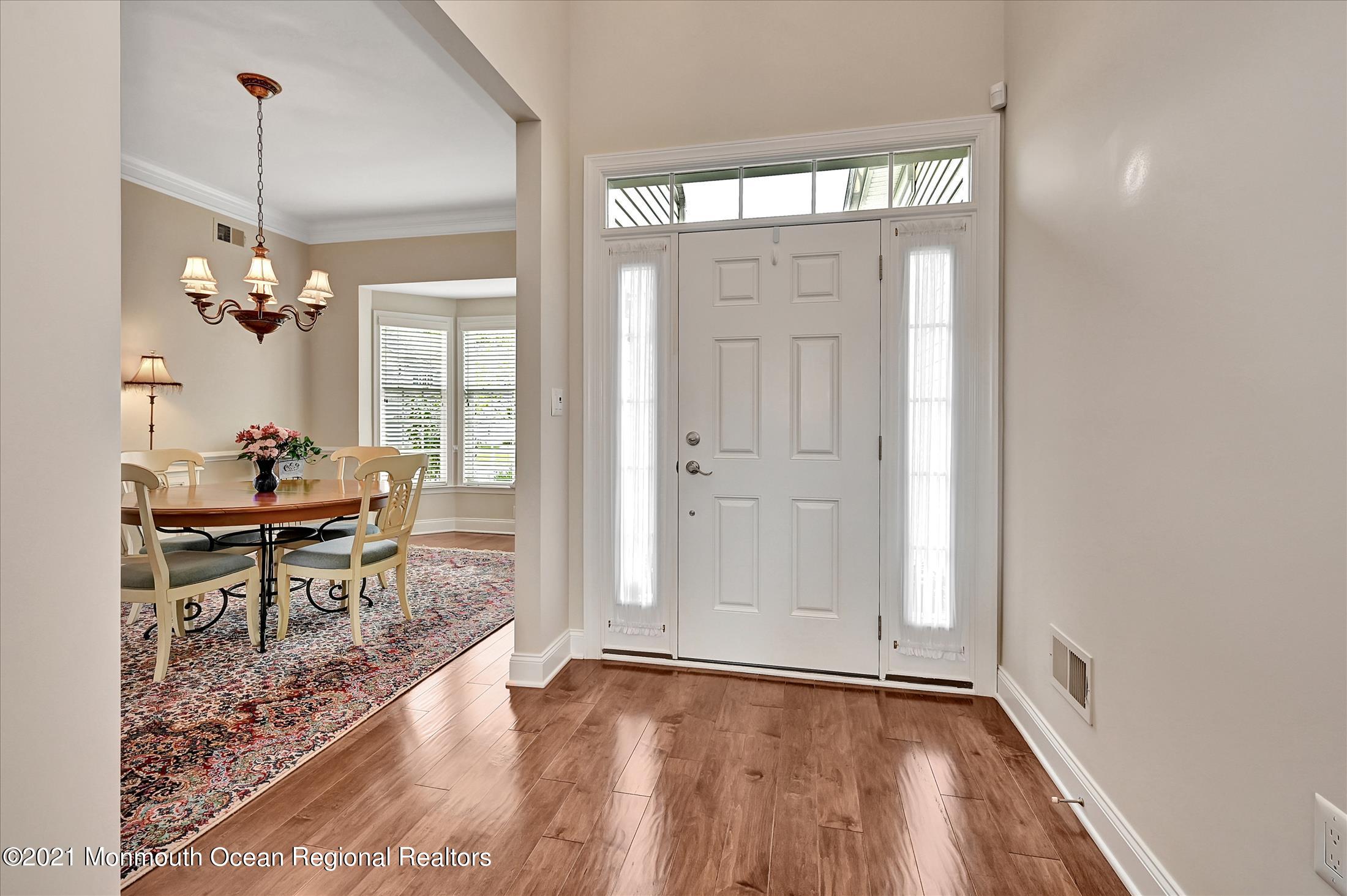 121 Sunset Drive Tinton Falls, NJ 07724 - Photo 3 of 40 a dining room with wooden floor a chandelier a glass table and windows