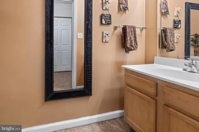 a view of a hallway with wooden floor and a bathroom
