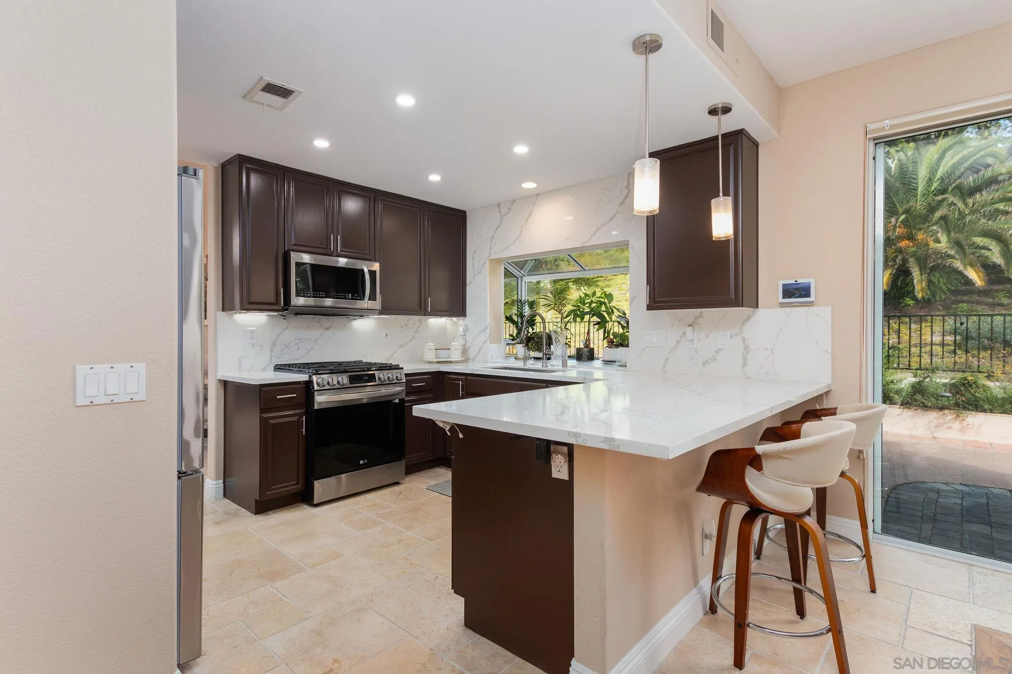 4532 Avenida Privado Oceanside, CA 92057 - Photo 11 of 40 a kitchen with stainless steel appliances kitchen island granite countertop a stove a refrigerator a sink a dining table and chairs with wooden floor