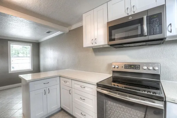 a kitchen with stainless steel appliances white cabinets and a stove top oven