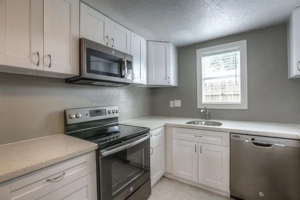 a kitchen with white cabinets appliances and sink