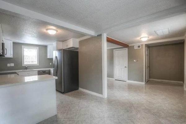 a view of an empty room and a kitchen