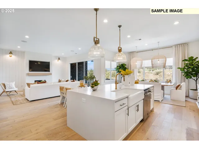 a kitchen with stainless steel appliances a sink a stove top oven a dining table with wooden floor