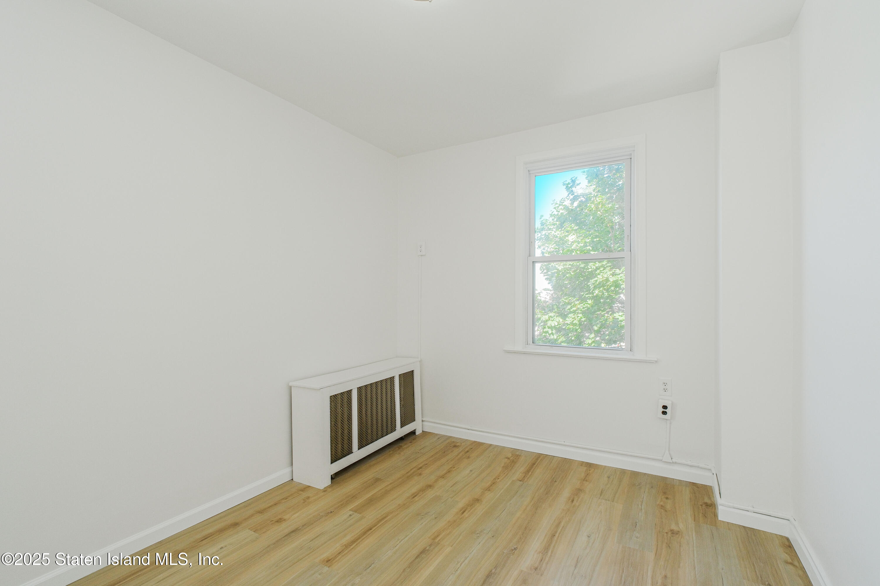 435 Castleton Avenue Staten Island, NY 10301 - Photo 12 of 47 a view of an empty room with wooden floor and a window