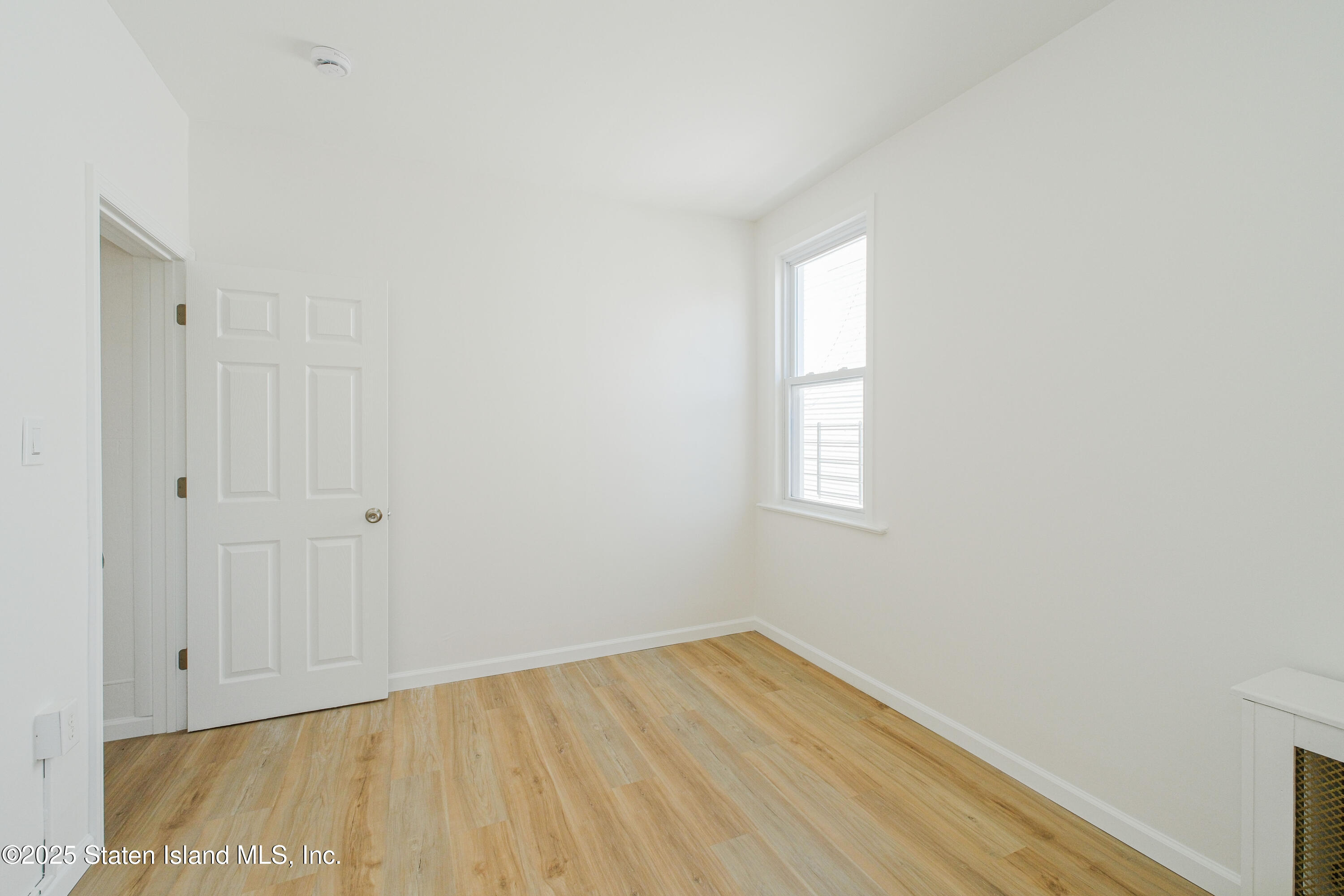 435 Castleton Avenue Staten Island, NY 10301 - Photo 14 of 47 a view of an empty room with wooden floor and a window
