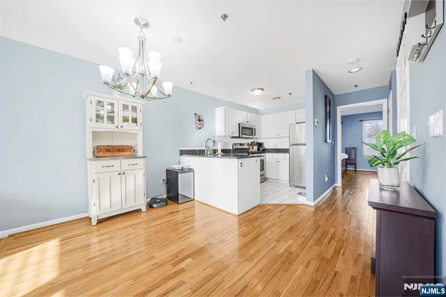 a view of a kitchen with kitchen island wooden floor stainless steel appliances and cabinets