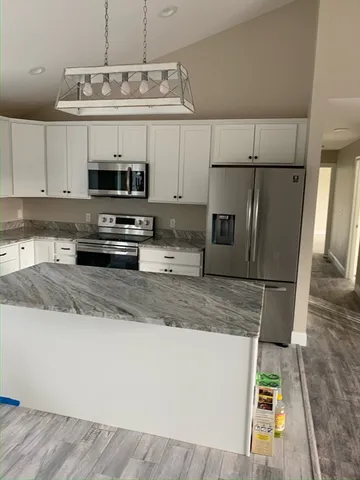 a kitchen with stainless steel appliances granite countertop a sink a stove a microwave a refrigerator a counter top and cabinets