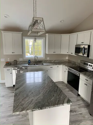 a kitchen with granite countertop a stove a sink a counter space and cabinets