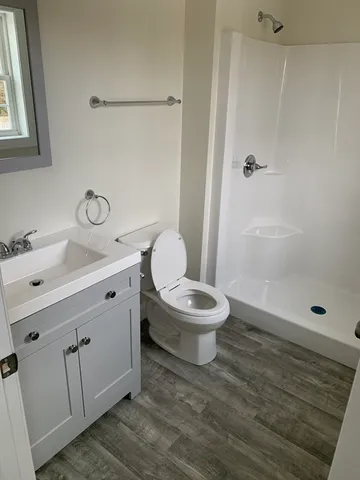 a bathroom with a toilet a sink a mirror and shower