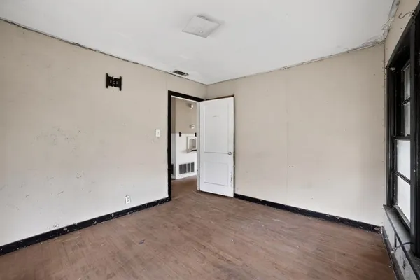 an empty room with wooden floor and window