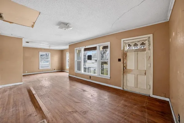 a view of an empty room with a window and wooden floor