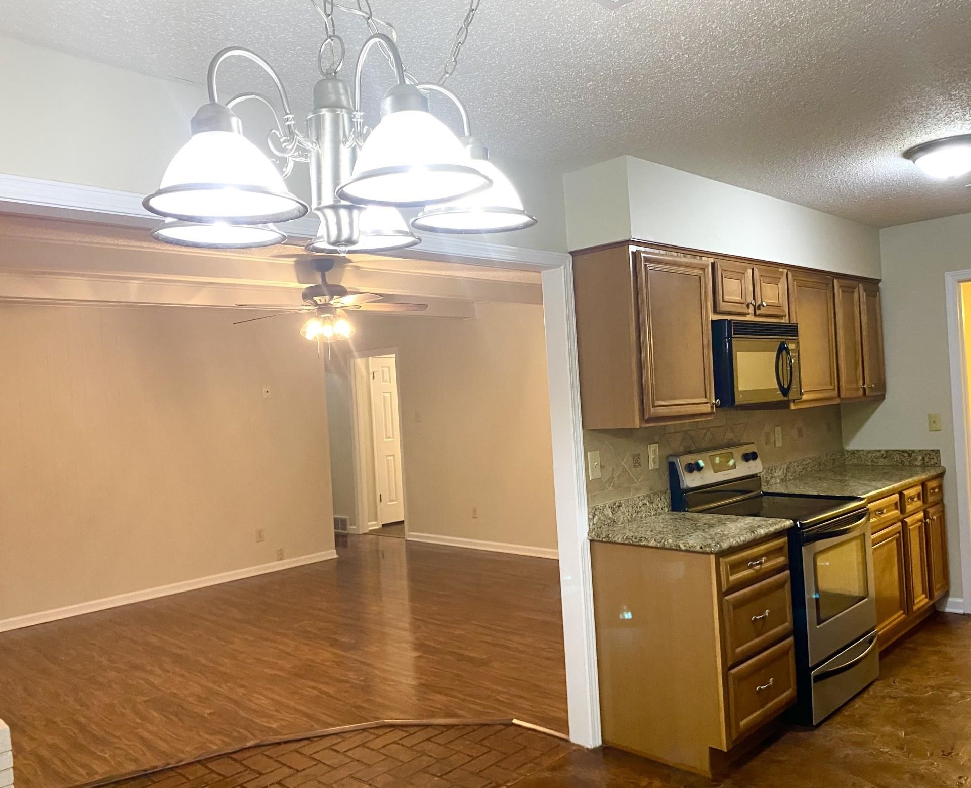 7918 Farmingdale Road Germantown, TN 38138 - Photo 3 of 12 Kitchen with ceiling fan with notable chandelier, tasteful backsplash, dark wood-type flooring, a textured ceiling, and stainless steel electric range