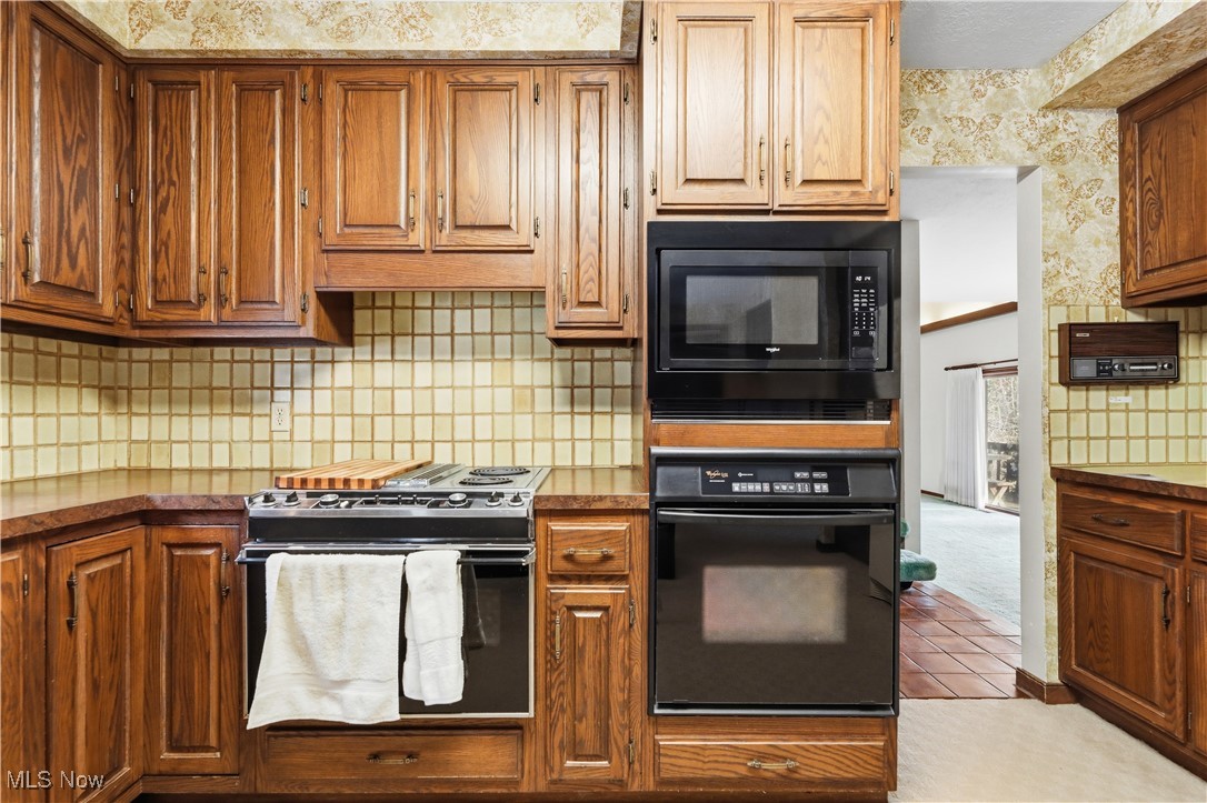 7014 River Styx Road Medina, OH 44256 - Photo 15 of 49 Kitchen with black appliances, backsplash, wallpapered walls, light tile patterned flooring, and brown cabinets
